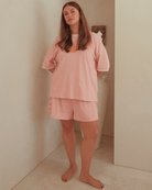 Woman wearing a pink pajama set standing in a bathroom.