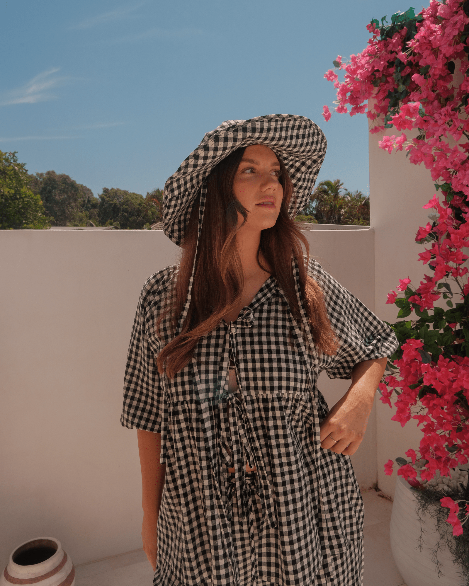 Woman in spring black gingham co-ord set with a matching cottage core wide-brimmed hat with adjustable neck ties. 