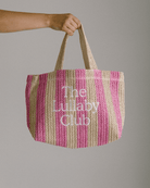 Striped pink & beige raffia holiday tote with 'The Lullaby Club' embroidered on the front.
