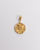 A gold-plated stainless steel charm featuring the Tree of Life design with a sunburst pattern and small decorative stones.