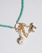 Necklace with gold and green charms on a light gray background