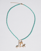 Turquoise beaded necklace with gold charm on a light gray background