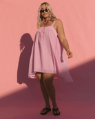 Woman wearing a pink dress against a pink background