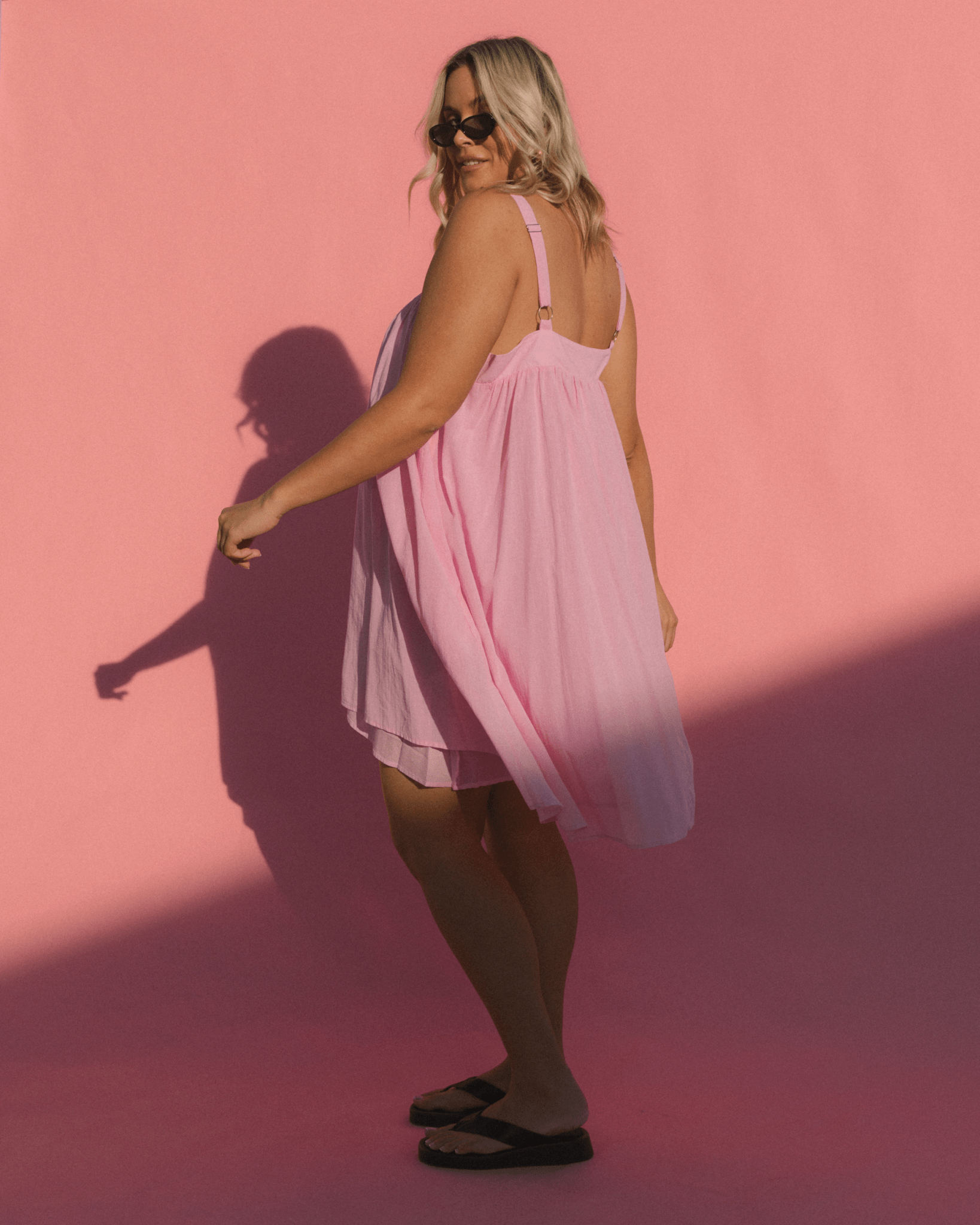 Woman swinging in flowy spring mini dress exposing the adjustable straps on the dress. 