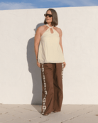 Women wearing stylish outfit of pale yellow cotton halter top & brown cotton long lounge pants with star detailing down the side-seams. 